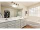 Bright bathroom features double sinks, a large mirror, a tub, and a glass block window at 14099 W Riviera Dr, Surprise, AZ 85379