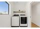 Bright laundry room with front load washer/dryer and wood shelves, window with great view at 14401 N 60Th Pl, Scottsdale, AZ 85254