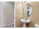 Neat powder room with a pedestal sink, oval mirror, and adjacent doorway at 15955 N Cristine Ln, Surprise, AZ 85388