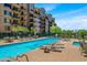 Community pool featuring lounge chairs, umbrellas, and access to condo amenities with mature landscaping at 17 W Vernon Ave # 508, Phoenix, AZ 85003