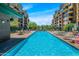 Pool area with lounge chairs, tables, umbrellas, and adjacent condominium building at 17 W Vernon Ave # 508, Phoenix, AZ 85003