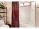Bright bathroom features a tub with a red shower curtain and a decorative shelving unit at 17153 W Gambit Trl, Surprise, AZ 85387