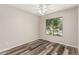 Light-filled bedroom showcasing modern plank flooring, a ceiling fan, and large window for natural light at 17828 W Calavar Rd, Surprise, AZ 85388