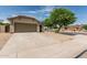 Well-maintained one-story home features desert landscaping, a tile roof, and a spacious concrete driveway to the two-car garage at 17828 W Calavar Rd, Surprise, AZ 85388