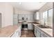 Well-lit kitchen featuring modern stainless appliances, tile floors, light gray cabinets and a window at 17828 W Calavar Rd, Surprise, AZ 85388