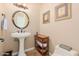 Charming powder room with a pedestal sink, decorative mirror, and framed artwork, perfect for guests' convenience at 18029 W San Miguel Ave, Litchfield Park, AZ 85340