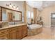 Elegant bathroom featuring a soaking tub, granite counters, and a large framed mirror with decorative lighting at 18029 W San Miguel Ave, Litchfield Park, AZ 85340