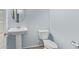 Well-lit half bathroom with pedestal sink, mirror, and standard toilet at 18637 W Williams Rd, Surprise, AZ 85387