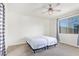 Neutral bedroom with ceiling fan, large window, and plush carpet flooring, bathed in sunlight at 18637 W Williams Rd, Surprise, AZ 85387