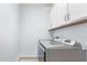 Functional laundry area with modern front-load washer and dryer and overhead cabinets at 18637 W Williams Rd, Surprise, AZ 85387