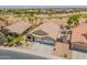 Aerial view of a home showing a three car garage and landscaping, with a desert golf course in the background at 22625 N Van Loo Dr, Maricopa, AZ 85138