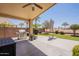 Covered back patio featuring an outdoor kitchen with a grill, a ceiling fan, and a grassy area for entertaining at 22625 N Van Loo Dr, Maricopa, AZ 85138