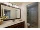 Well-lit bathroom with a dark wood vanity, framed mirror, and an adjacent glass-enclosed shower at 22625 N Van Loo Dr, Maricopa, AZ 85138