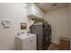 Functional laundry room with modern washer and dryer, a utility sink, and overhead storage cabinets at 22625 N Van Loo Dr, Maricopa, AZ 85138