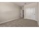 An empty bedroom featuring neutral-toned walls, carpet, and sliding closet doors for a serene and minimalist aesthetic at 22913 N 183Rd Dr, Surprise, AZ 85387