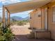 Exterior view of a beige home featuring an outdoor covered patio and step entrance, with desert vegetation at 270 S Ralston Rd, Maricopa, AZ 85139