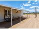 Exterior view of a white house with a covered porch and access stairs on a large dirt lot at 270 S Ralston Rd, Maricopa, AZ 85139