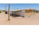 Beige home featuring white trim, windowed porch, and a utility pole, surrounded by a desert landscape under a clear sky at 270 S Ralston Rd, Maricopa, AZ 85139
