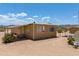 Side view of a tan home on a dirt lot with desert vegetation and an outbuilding, under a clear blue sky at 270 S Ralston Rd, Maricopa, AZ 85139