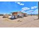 An exterior view of house with a water tank on a dirt lot under a blue sky at 270 S Ralston Rd, Maricopa, AZ 85139