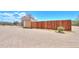 View of a wooden fence, small storage shed, and desert landscape on a sunny day at 270 S Ralston Rd, Maricopa, AZ 85139