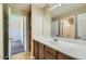 Well-lit bathroom featuring a spacious vanity with a large mirror, tile floor, and access to a bedroom at 29828 N 72Nd Ln, Peoria, AZ 85383
