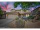 Charming two-story home featuring a two-car garage, stone accents, and a well-manicured front yard under a colorful sky at 29828 N 72Nd Ln, Peoria, AZ 85383