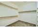An empty walk-in closet with wooden shelves and neutral carpet at 29828 N 72Nd Ln, Peoria, AZ 85383