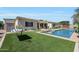 Outdoor living space with in-ground pool, covered patio, and lush artificial grass at 3125 W Desert Ln, Laveen, AZ 85339