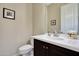 Neutral bathroom featuring a single sink with a dark wood vanity, framed mirror, and decorative artwork at 3125 W Desert Ln, Laveen, AZ 85339