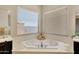 Corner bathtub with decorative accents by two large windows with bright neutral decor at 3125 W Desert Ln, Laveen, AZ 85339