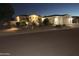 Inviting desert home with three-car garage and manicured landscaping, beautifully lit at twilight at 3125 W Desert Ln, Laveen, AZ 85339