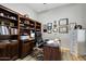 Well-lit home office features a desk, chair, bookshelf and various awards and accolades at 3125 W Desert Ln, Laveen, AZ 85339