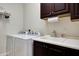 Functional laundry room with a white sink, dark wood cabinets, washer, and dryer at 3125 W Desert Ln, Laveen, AZ 85339
