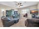 Comfortable living room featuring plush leather furniture, a ceiling fan, a TV and ample natural light at 3125 W Desert Ln, Laveen, AZ 85339