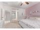 Bright bedroom featuring a ceiling fan, ensuite bathroom, neutral carpet and a light pink accent wall at 40010 W Ganly Way, Maricopa, AZ 85138