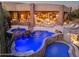 Backyard featuring a blue-lit pool, spa with a waterfall, and an outdoor living area with a cozy fire pit at 41667 N 113Th Pl, Scottsdale, AZ 85262