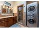 Bathroom with dark wood cabinets, stone-tiled shower, and stacked washer and dryer at 41667 N 113Th Pl, Scottsdale, AZ 85262