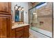 Elegant bathroom features a wood vanity with granite counter and a tiled shower with glass door at 41667 N 113Th Pl, Scottsdale, AZ 85262