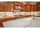Close-up on the marble island with white sink, stainless faucet, stainless stove, and custom cabinets at 41667 N 113Th Pl, Scottsdale, AZ 85262