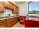 Well-equipped laundry room with custom cabinets, granite counters, red washer/dryer, and scenic views at 41667 N 113Th Pl, Scottsdale, AZ 85262