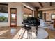Open living room with grand piano and access to outdoor patio at 41667 N 113Th Pl, Scottsdale, AZ 85262