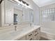 Bright bathroom featuring dual sinks, a large mirror and tub with a glass block window at 43690 W Knauss Dr, Maricopa, AZ 85138