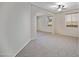 Open concept living room featuring carpet flooring, arched doorway, and large windows at 43690 W Knauss Dr, Maricopa, AZ 85138