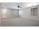 Large, carpeted living room with ample light, ceiling fan, and white door with window at 43690 W Knauss Dr, Maricopa, AZ 85138