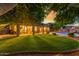 Expansive backyard featuring lush lawn, inviting pool, covered patio, mature trees, and ambient lighting at 6918 W Villa Hermosa W --, Glendale, AZ 85310