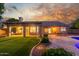 Stunning backyard showcasing a covered patio, green lawn, inviting pool, and beautifully landscaped surroundings at dusk at 6918 W Villa Hermosa W --, Glendale, AZ 85310