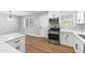Bright kitchen features stainless steel appliances, white cabinetry, and laminate wood flooring at 724 W Missouri Ave, Phoenix, AZ 85013