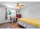 Bright bedroom with wood floors, desk, dresser, and a yellow patterned quilt at 8116 N 55Th Dr, Glendale, AZ 85302