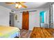 Bedroom featuring wood flooring, sliding barn door, and view to a bathroom at 8116 N 55Th Dr, Glendale, AZ 85302